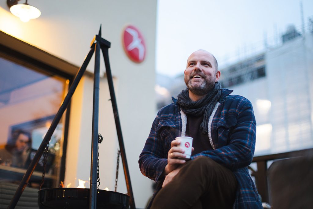 Einar Kleppe Holthe drikker kaffe, sitter ved bålpanne, ute foran Fuglen kaffebar.