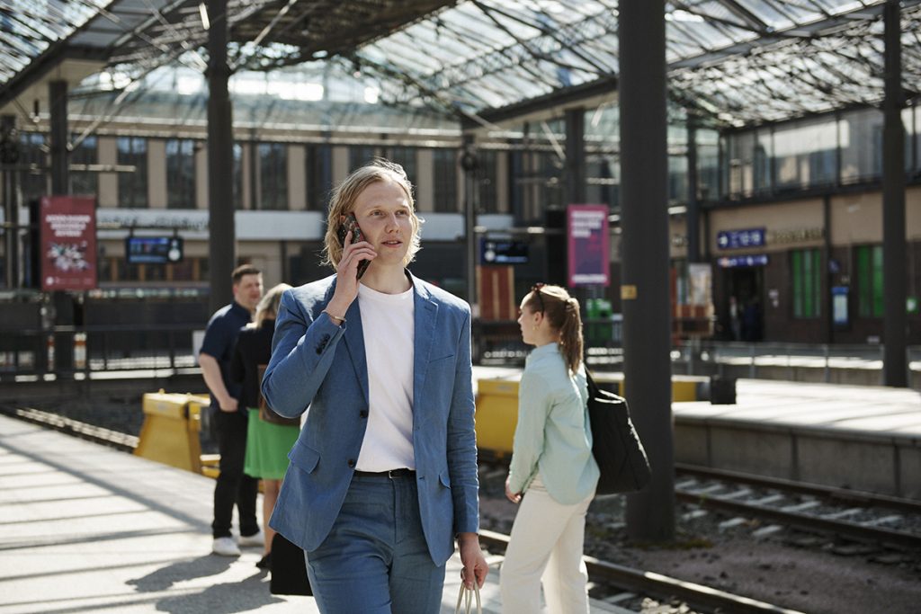 Reiseregning: mann på forretningsreise prater i telefonen på togstasjonen