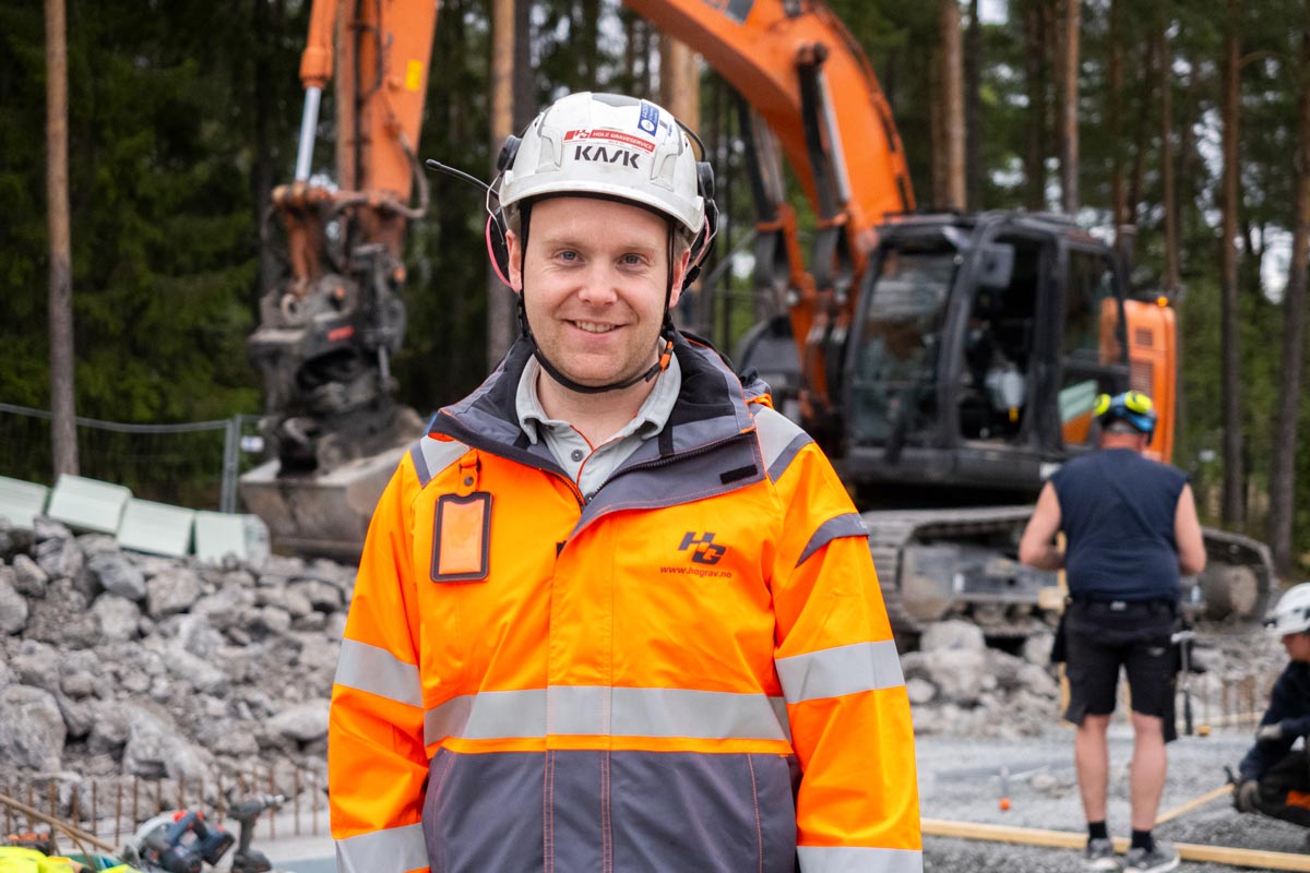 En bygningsarbeider i synlig jakke og hjelm smiler til kameraet mens han snakker om SmartDok og Tripletex