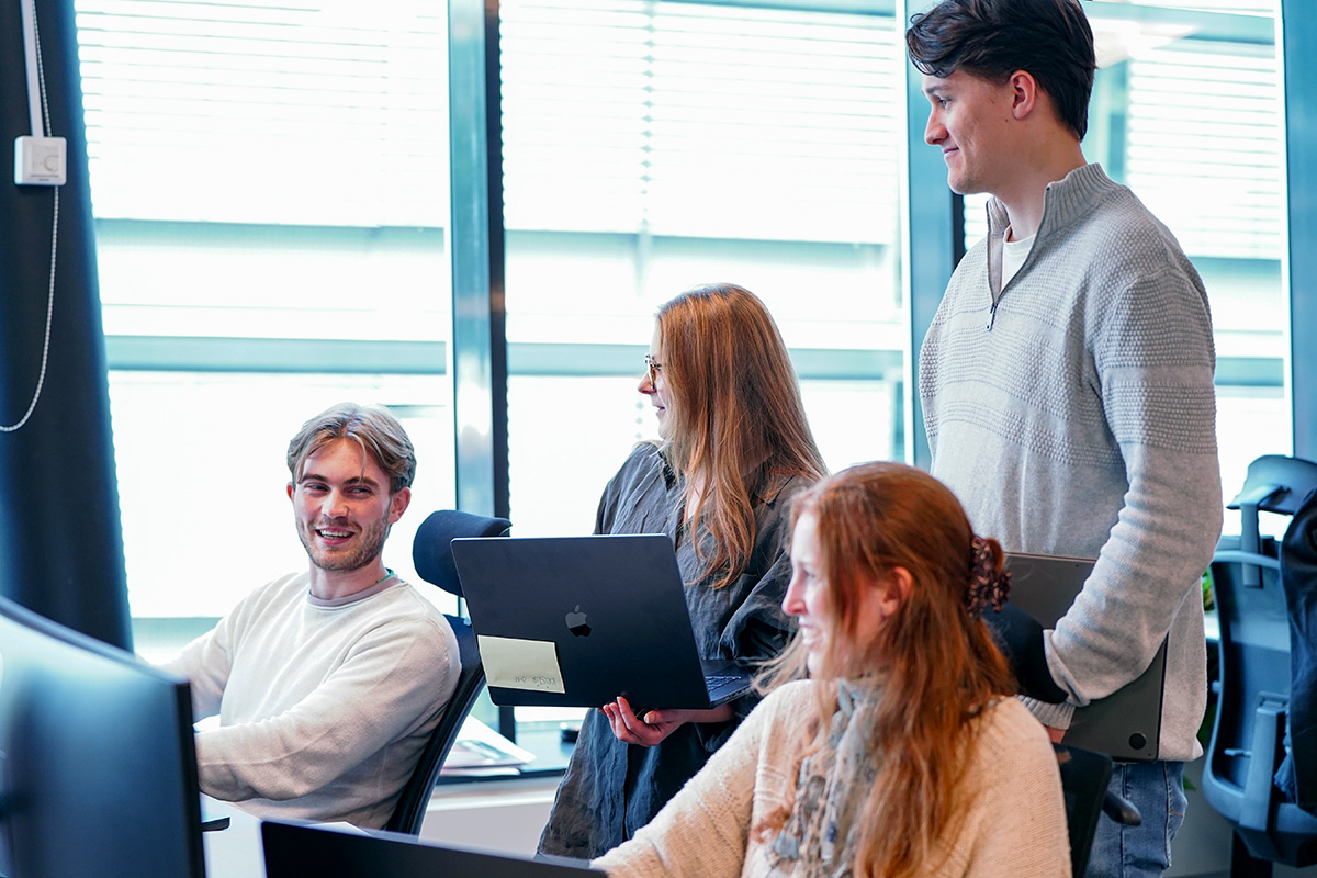 Fire personer i moderne kontormiljø, to sittende og to stående. Årets sommerstudenter i Tripletex har testet arbeidslivet.