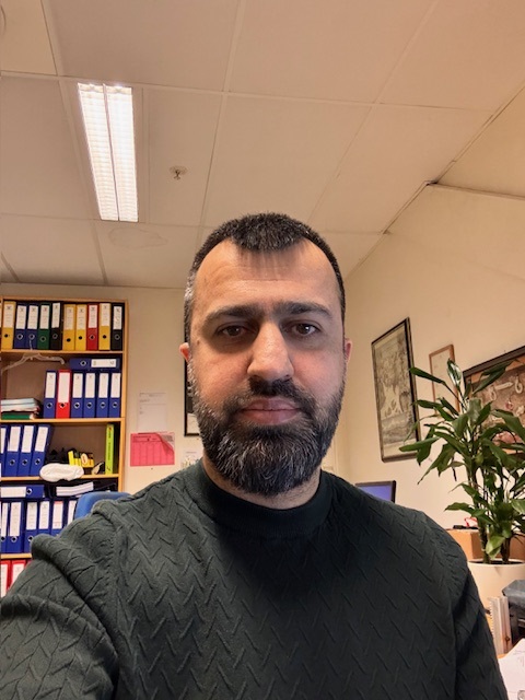 I en travel kontorsetting er en skjeggete mann fordypet i arbeidet sitt, omgitt av pent organiserte permer og en blomstrende plante. Fokuset hans forblir urokkelig mens han utnytter effektiviteten til Rackbeat for å strømlinjeforme oppgavene sine uten problemer.