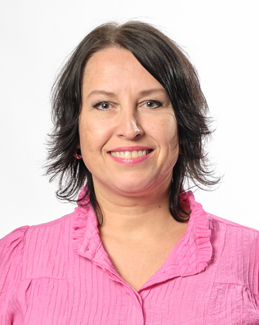 Birgitte Strand smiler mens hun har på seg en rosa bluse mot en hvit bakgrunn.