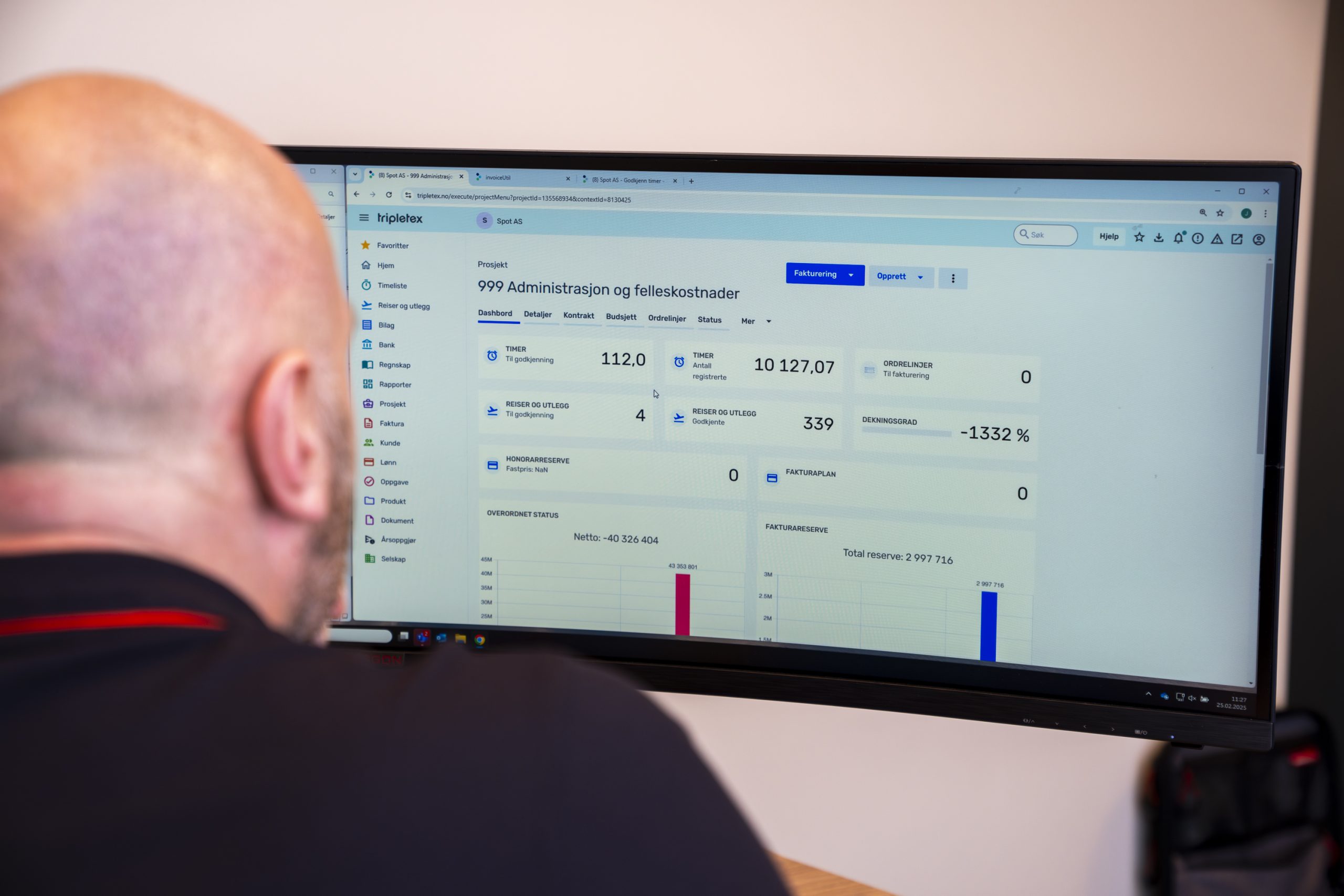 En person med et barbert hode ser på en dataskjerm som viser et dashbord med ulike statistikker og diagrammer.
