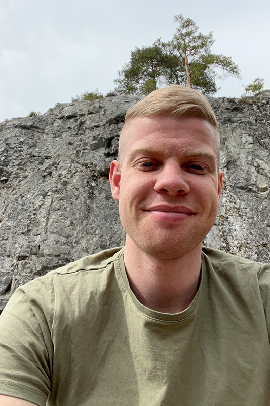 En person med kort, blondt hår og lysegrønn skjorte smiler til kameraet utendørs. Kjellemyr Elektro lager egne kontrollskjemaer med skjemabygger.