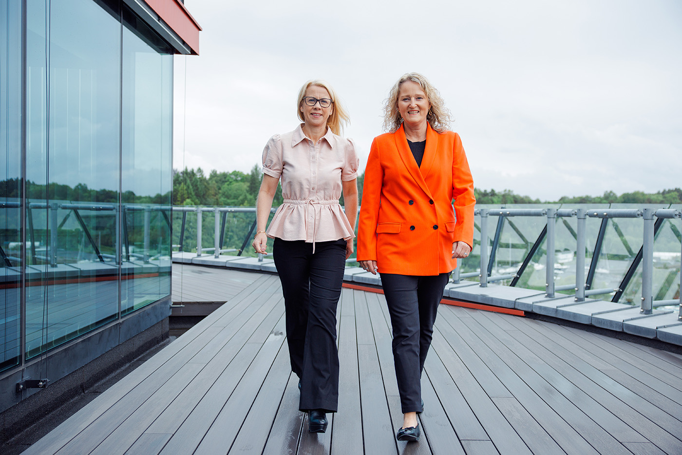 Lise Ekanger er direktør for strategiske kunderelasjoner i Tripletex. En kvinne med blondt hår og briller står smilende i et kontormiljø med pulter, skjermer og mennesker i bakgrunnen.