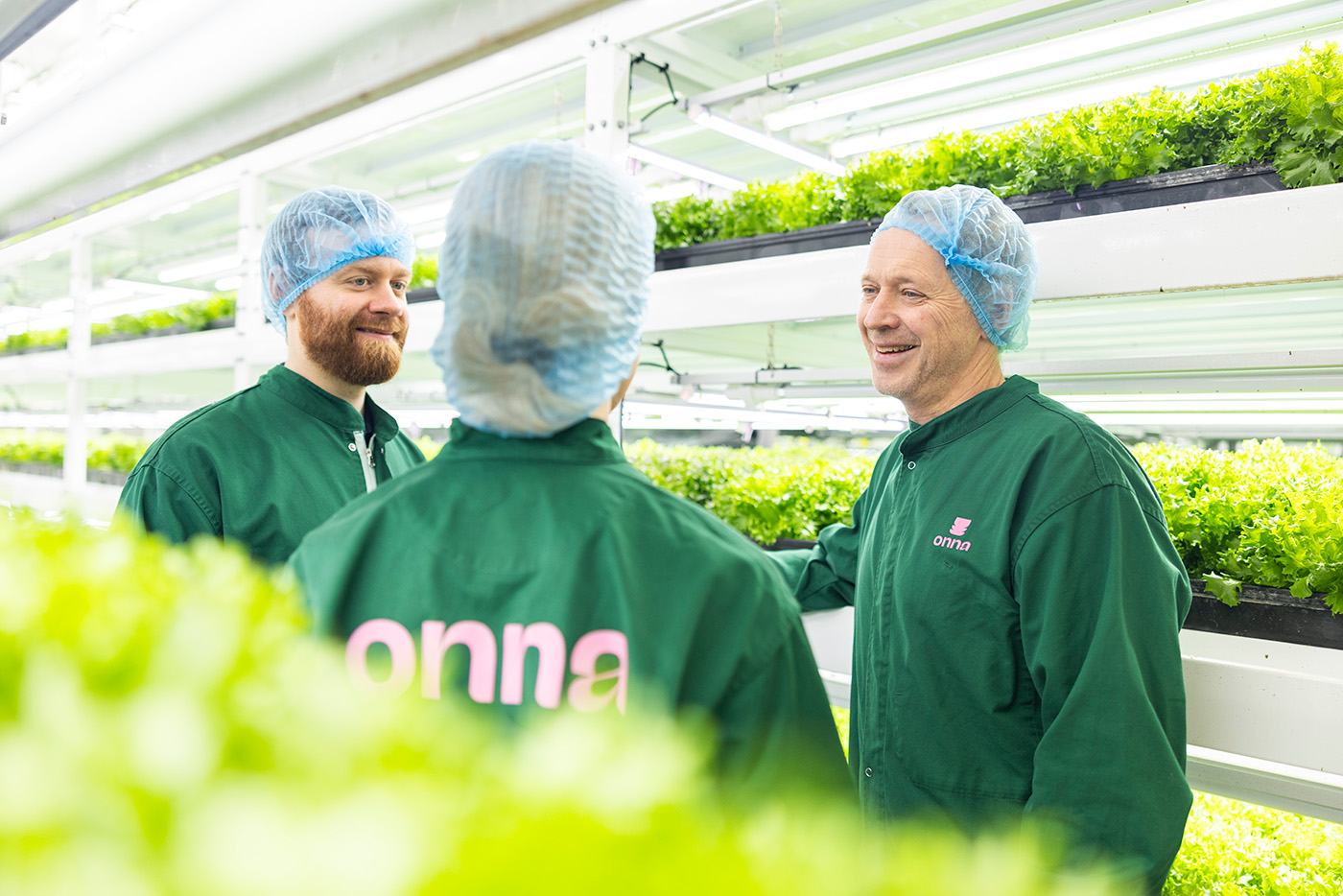 En laptop-skjerm viser et rapportdashboard på norsk, mens rosa oppbevaringsbokser er synlige gjennom et vindu i bakgrunnen.