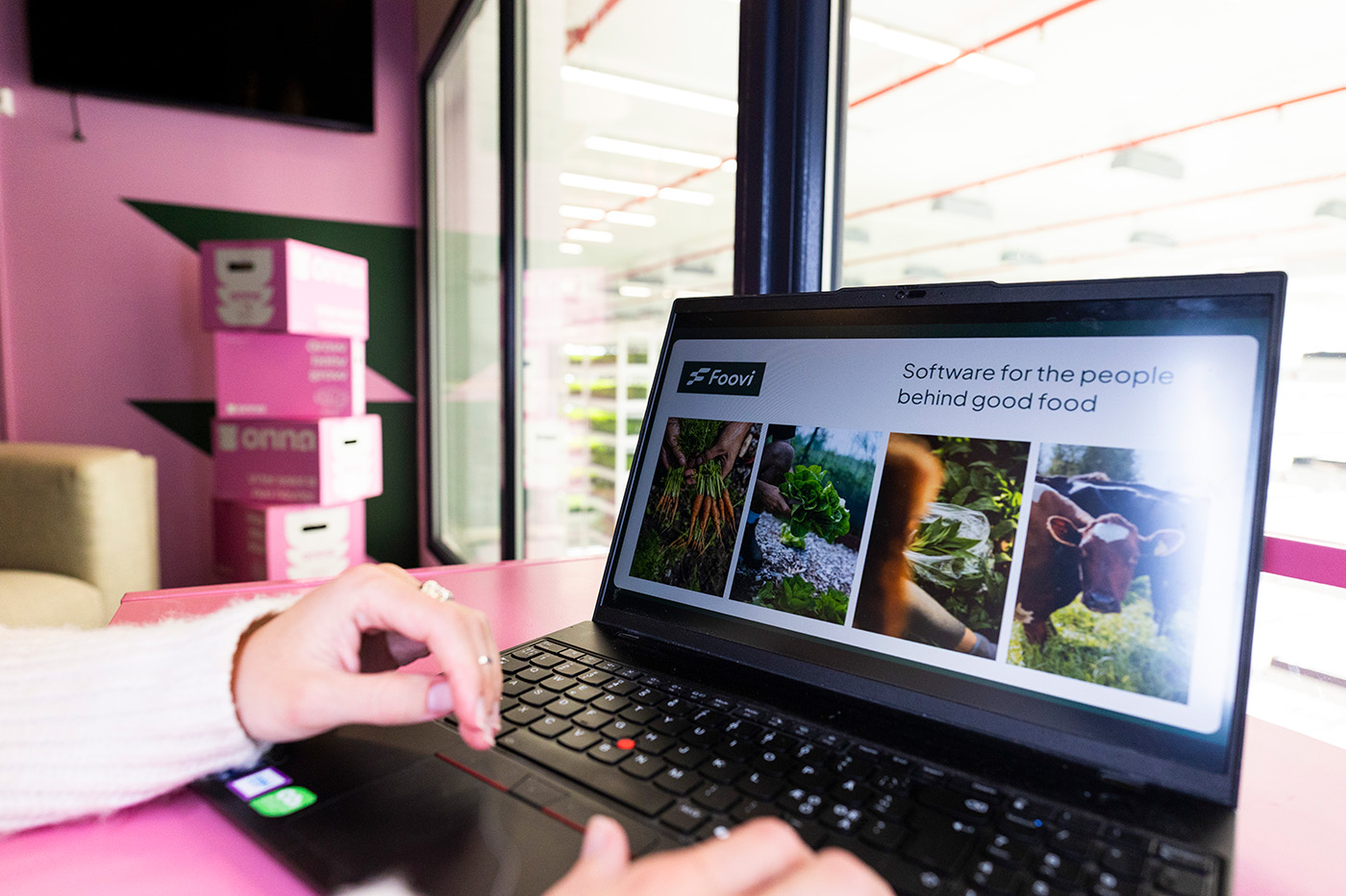 En person bruker en bærbar datamaskin som viser en nettside med tittelen "Software for the people behind good food" og bilder av planter, råvarer og en ku.