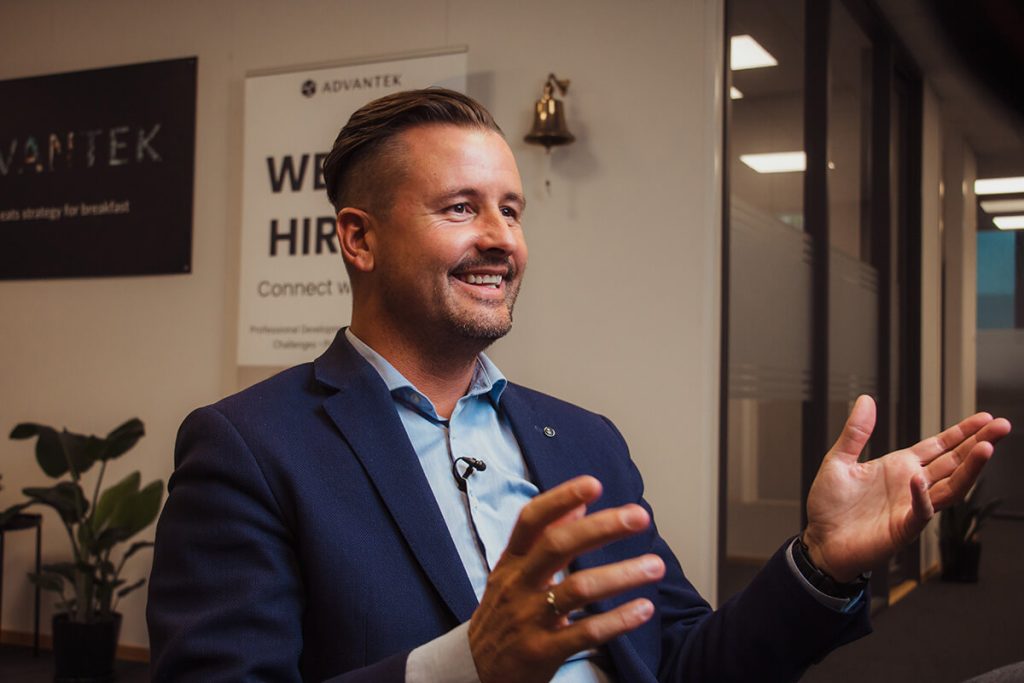 Arild André Lycke, VP i i Advantek Norge, fotografert i et kontormiljø med et "Vi ansetter"-skilt i bakgrunnen.