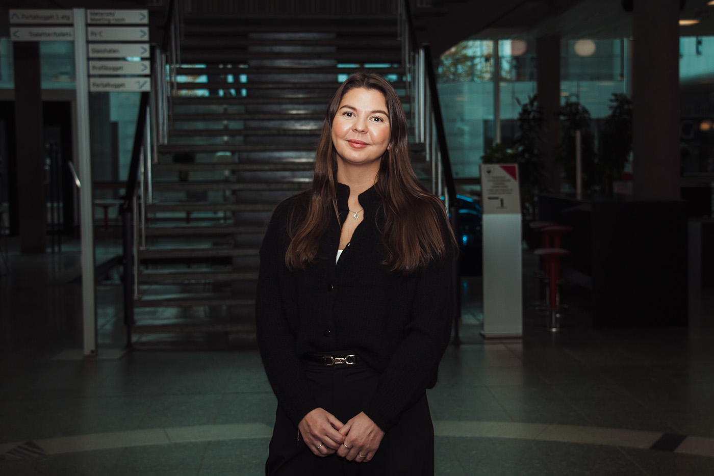 Lise Ekanger er direktør for strategiske kunderelasjoner i Tripletex. En kvinne med blondt hår og briller står smilende i et kontormiljø med pulter, skjermer og mennesker i bakgrunnen.