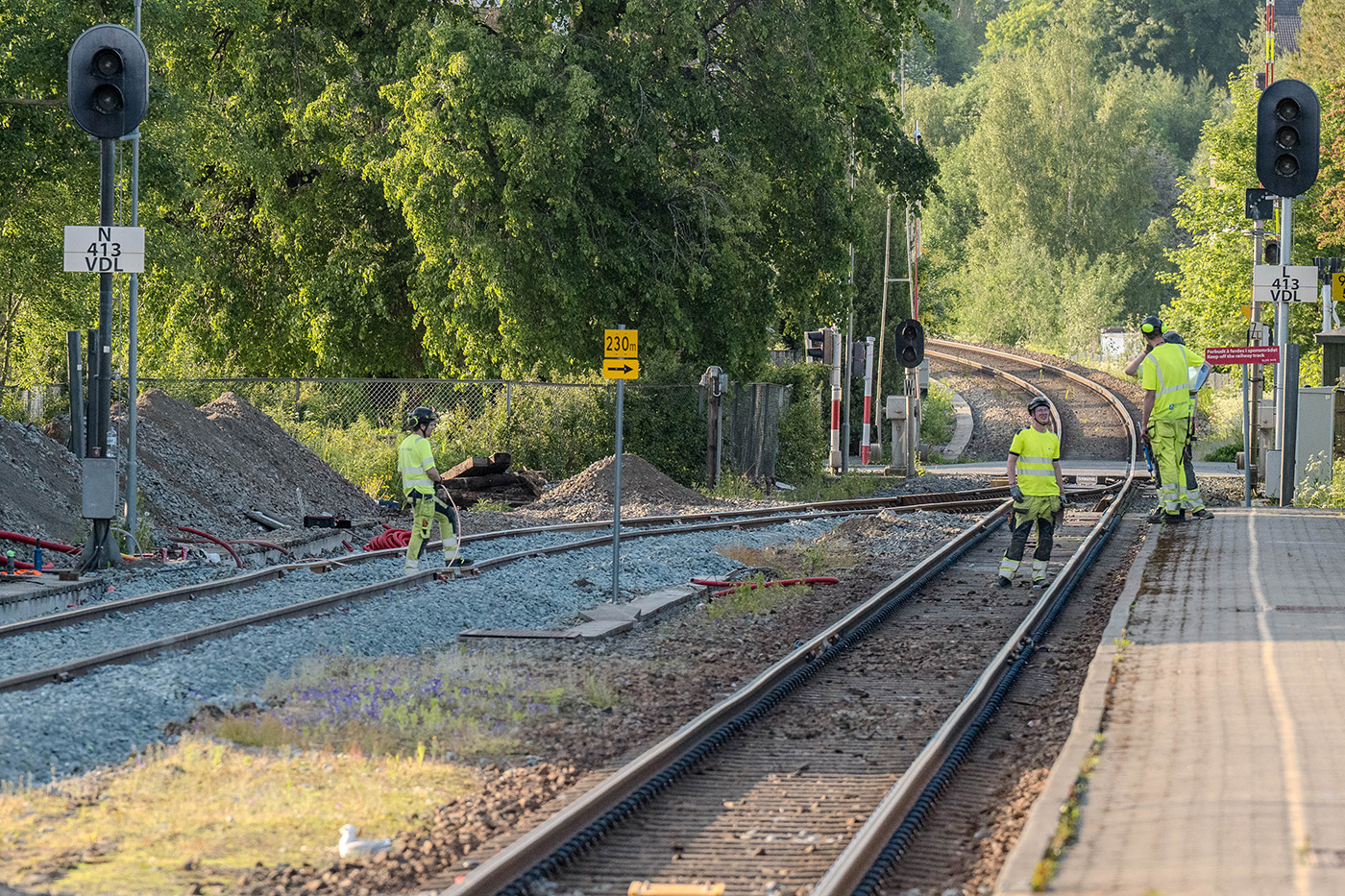Anleggsarbeidere fra Site Service Bane går på togskinner nær en jernbanestasjon