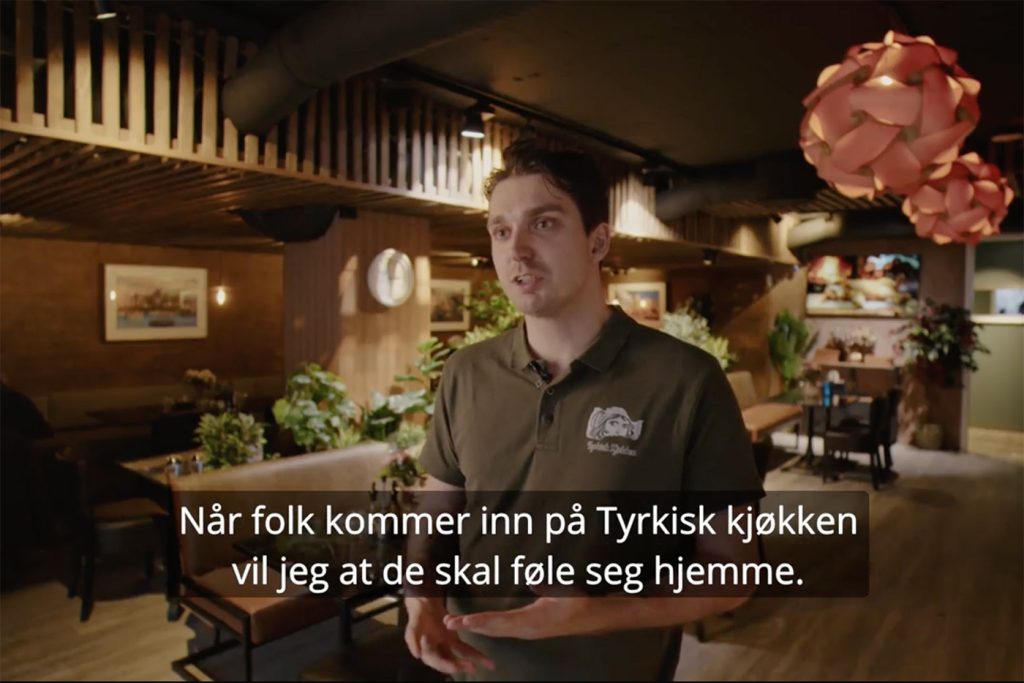 Skjermbilde fra Tyrkisk kjøkken. Daglig leder Alexander prater mot kamera, restauranten i bakgrunnen