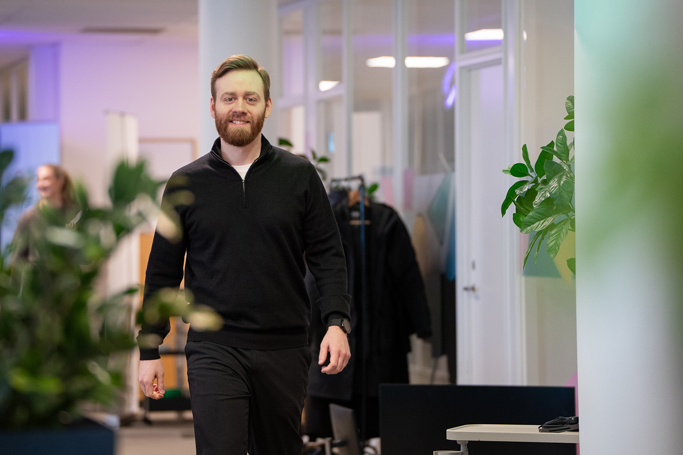 Kristian Bakke går gjennom kontorlandskap med grønne planter. Snakker om skattemeldingen og årsoppgjør