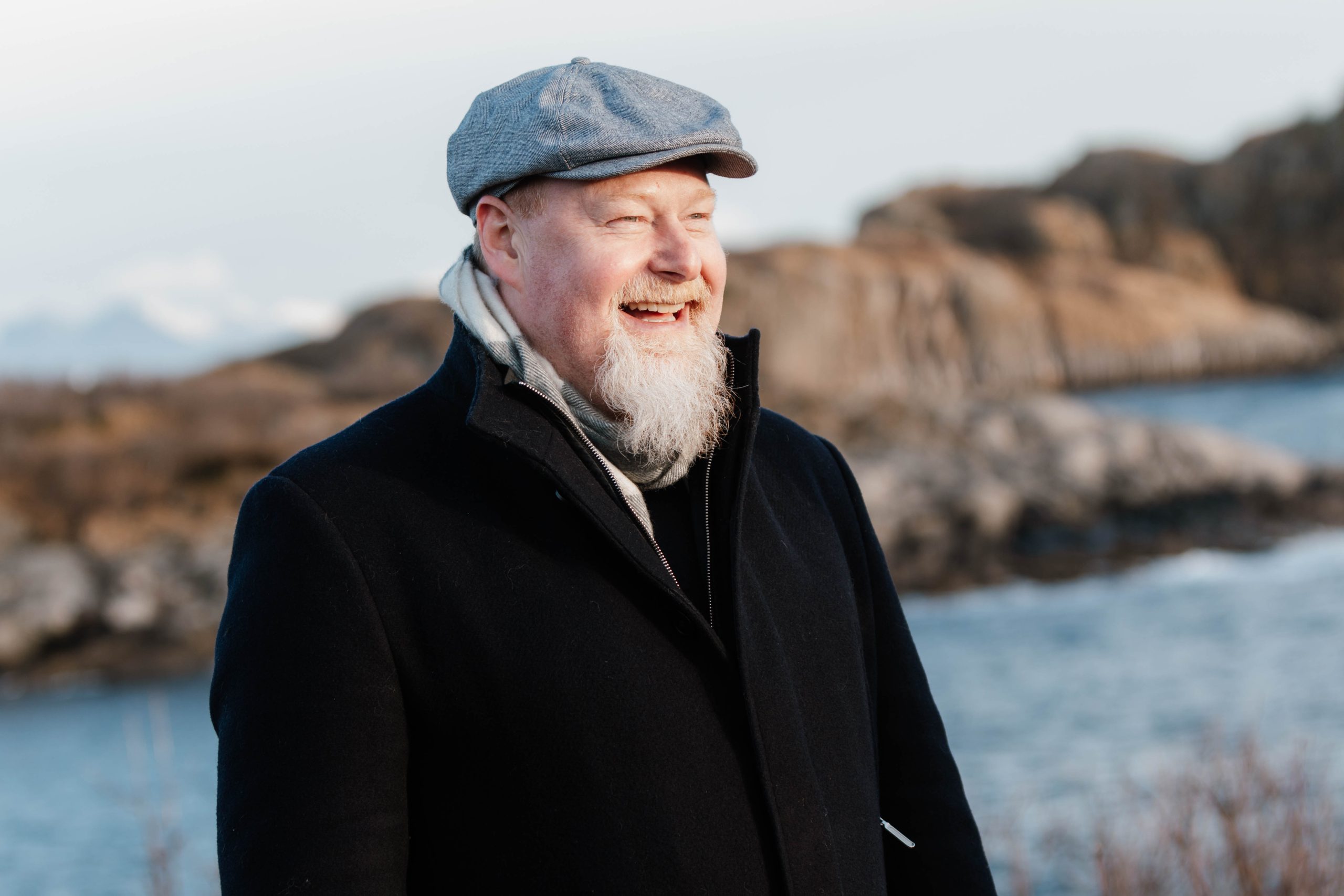 To menn står og snakker på et lite kafékjøkken; den ene holder et krus, mens den andre står ved disken med diverse kjøkkenutstyr.